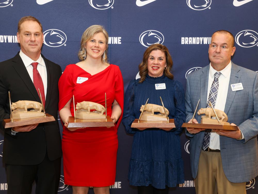 four people holding awards