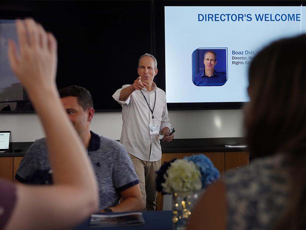 Man in white shirt points to someone