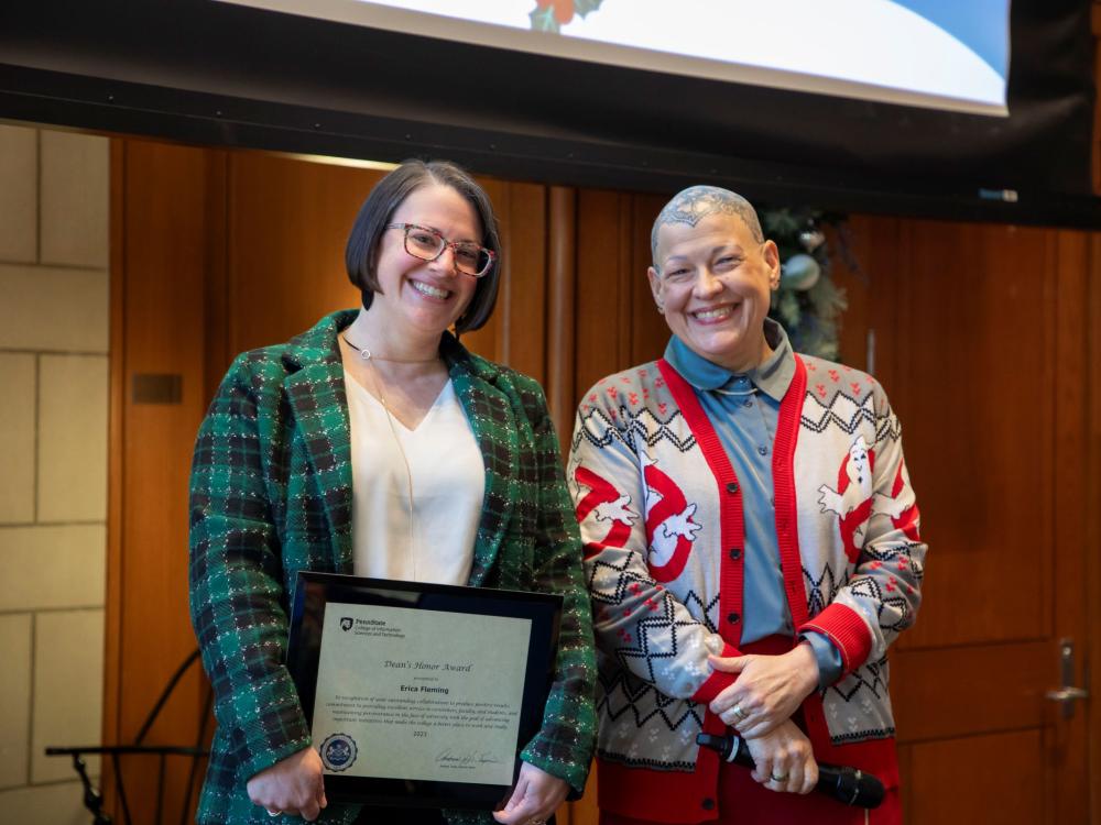 two smiling people display award certificate