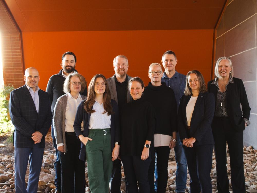 Photo of 10 people standing in front of a building.