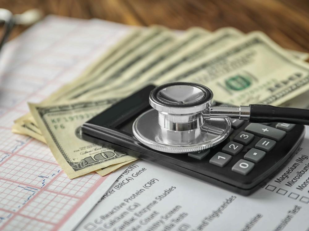 stethoscope on top of a pile of money and medical forms