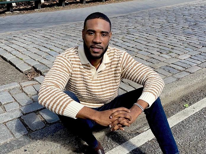 Young Black man sitting on a curb dressed in business casual clothing