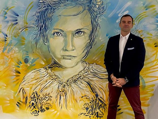 A man standing in front of a colorful painting of a child