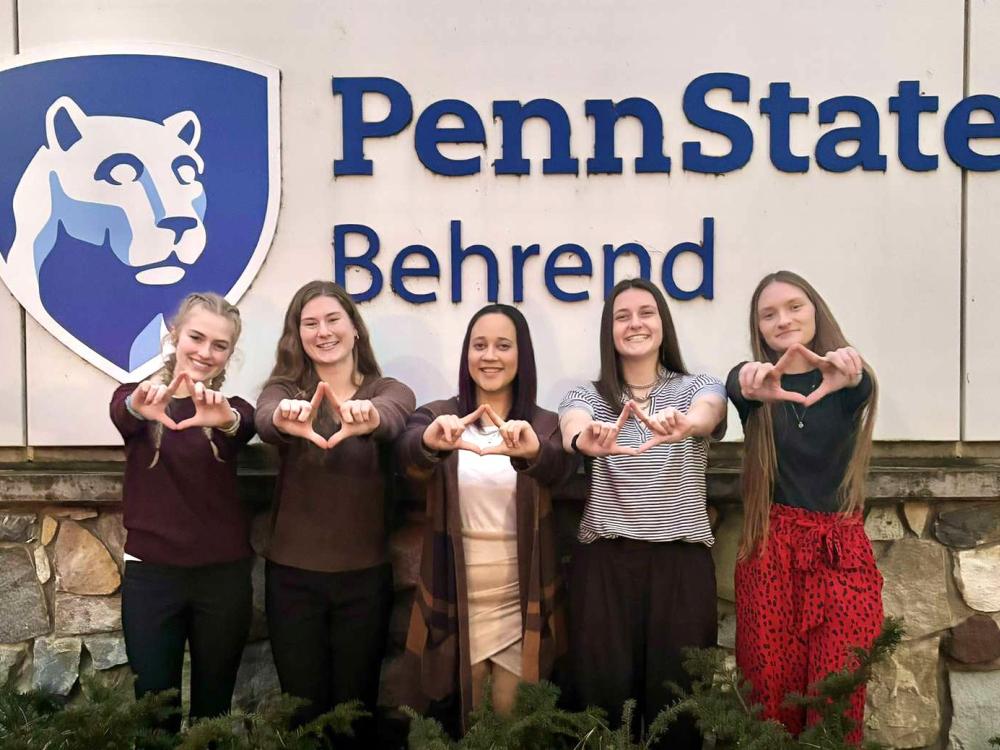 Five female students hold their hands up in the symbol for the Four Diamonds Fund.