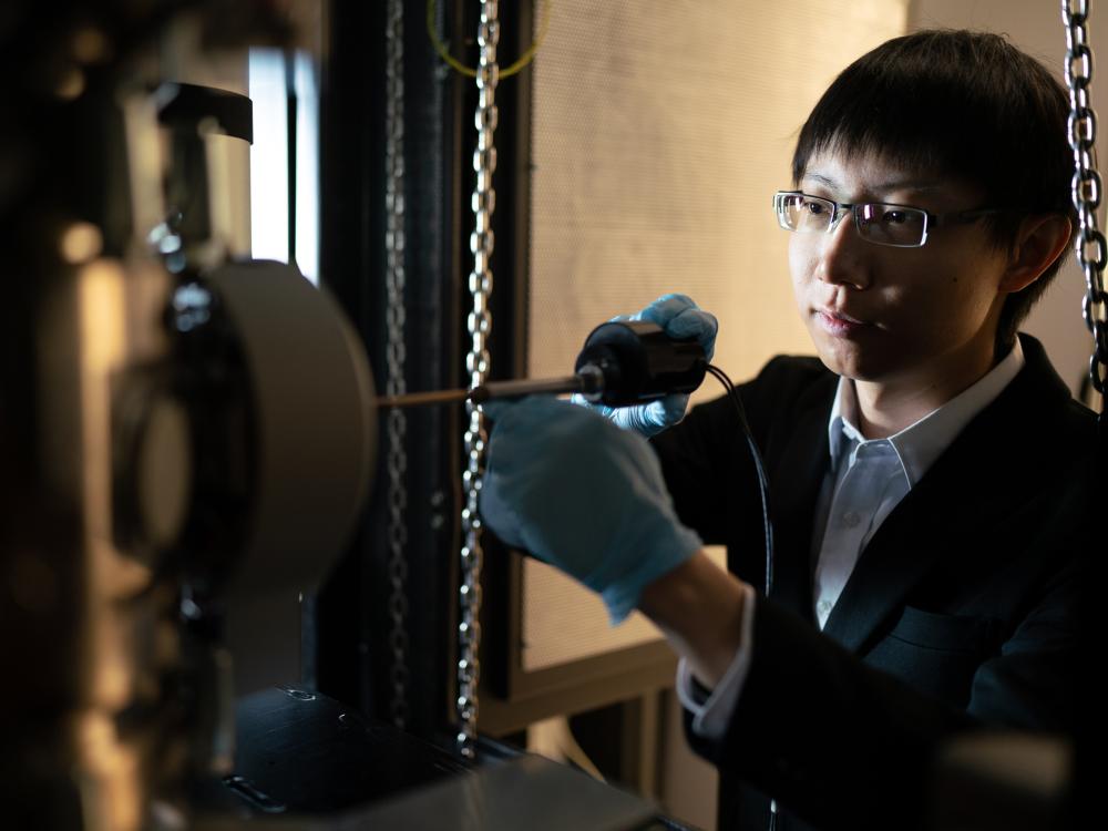 A person wearing glasses adjusts a piece of lab equipment