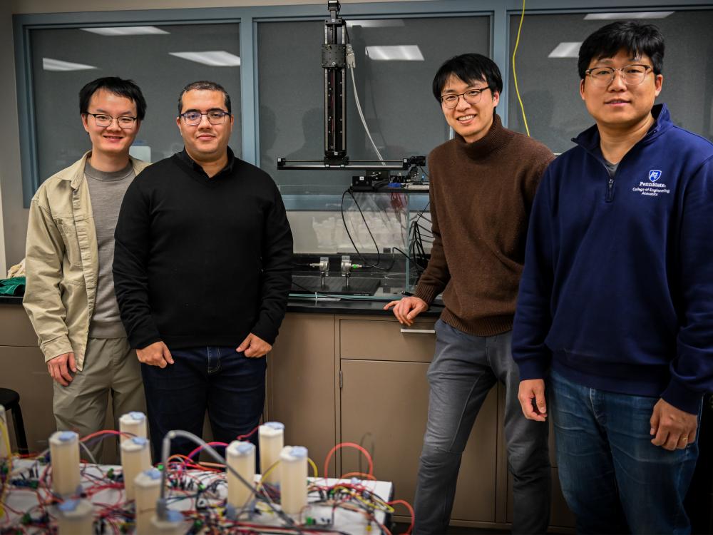 Four individuals pose near ultrasound lab equipment in a lab.