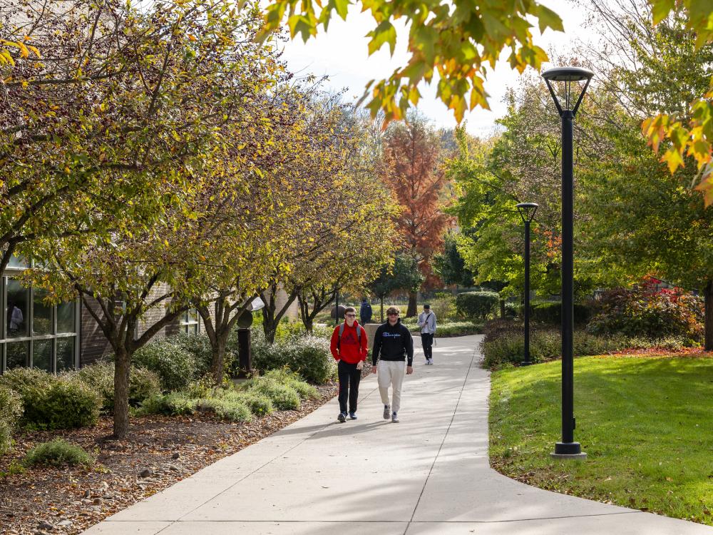Two male students walk to class surrounded by fall foliage