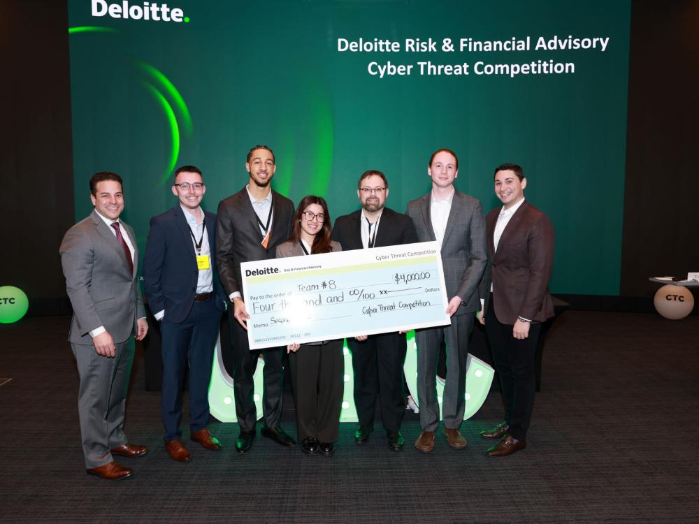 group of people in suits holding giant check against conference backdrop