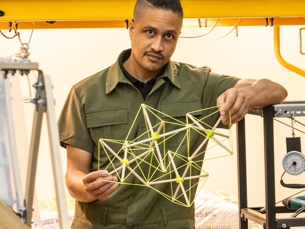 DK Osseo-Asare holding a model of a bamboo structure in his lab.