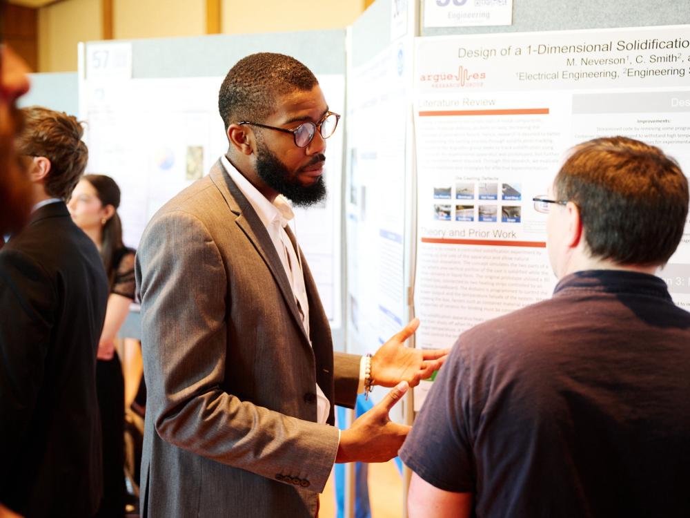 Student presenting research poster to faculty judge at 2023 Exhibition