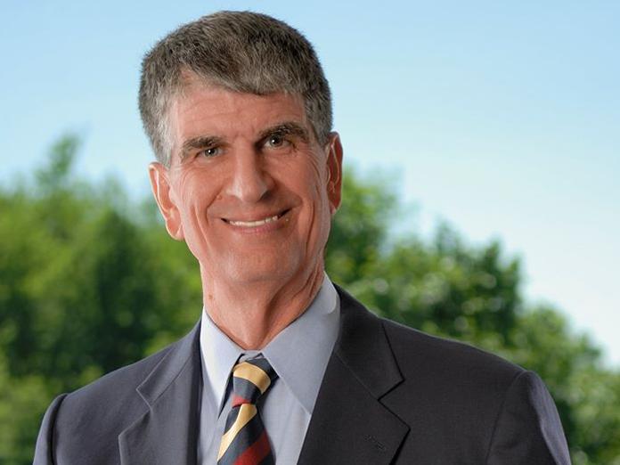 Older white male with gray hair and a suit smiling