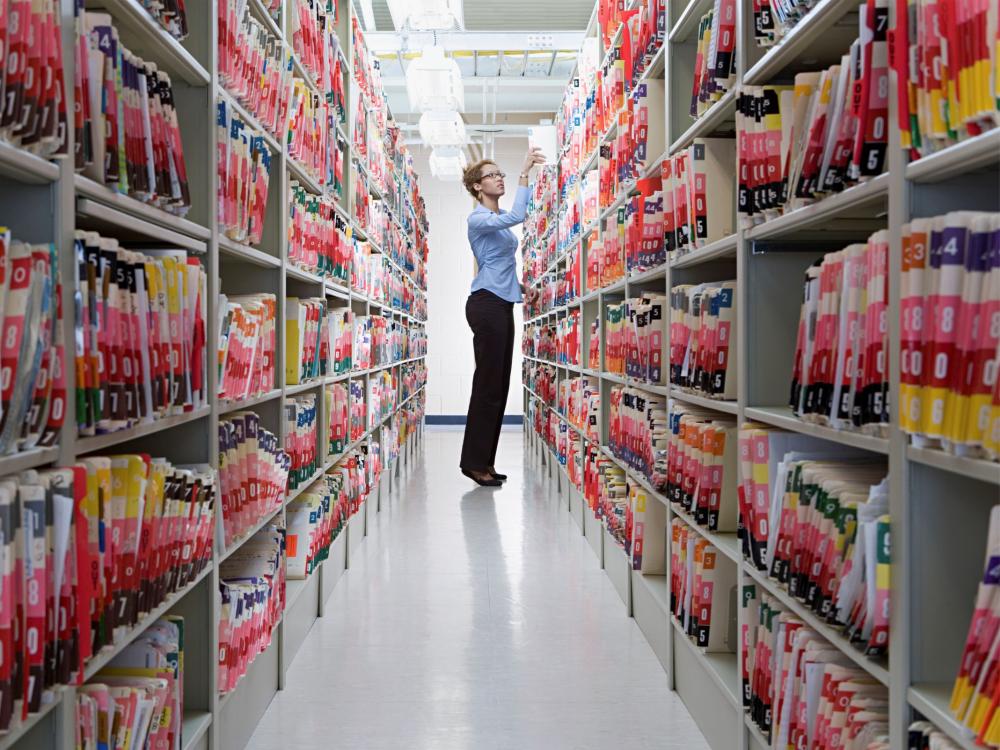 person standing by shelves of medical records
