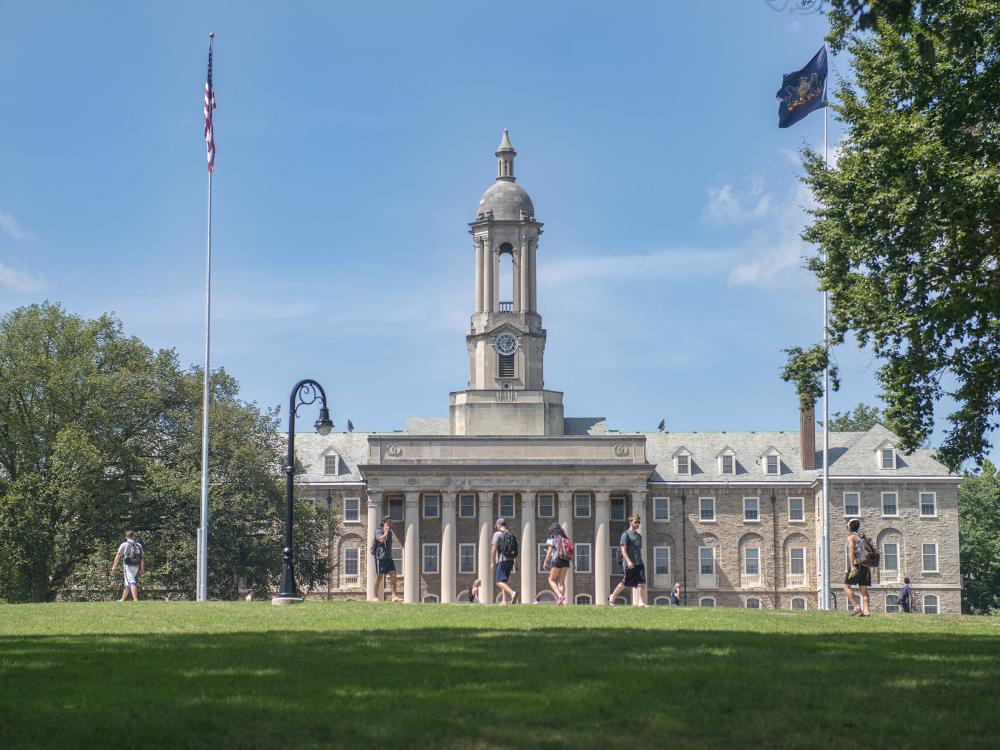 Exterior image of Old Main building at Penn State University Park with flag poles in the foreground