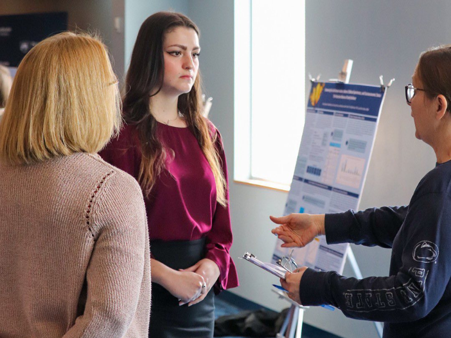 A student speaking with two judges in a classroom 