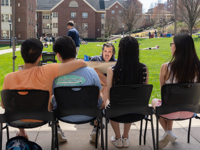 Four students sitting for a charicature portrait during a Residence Life carnival