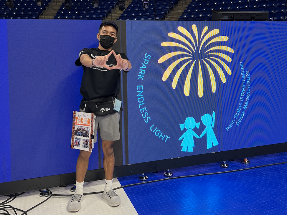 Jacob Santos setting up for THON weekend, doing the diamond hand sign, and wearing shorts and a mask. 