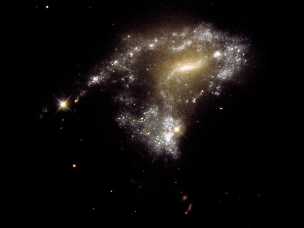 image of galaxy with long tail-like tendril spiraling of the edge