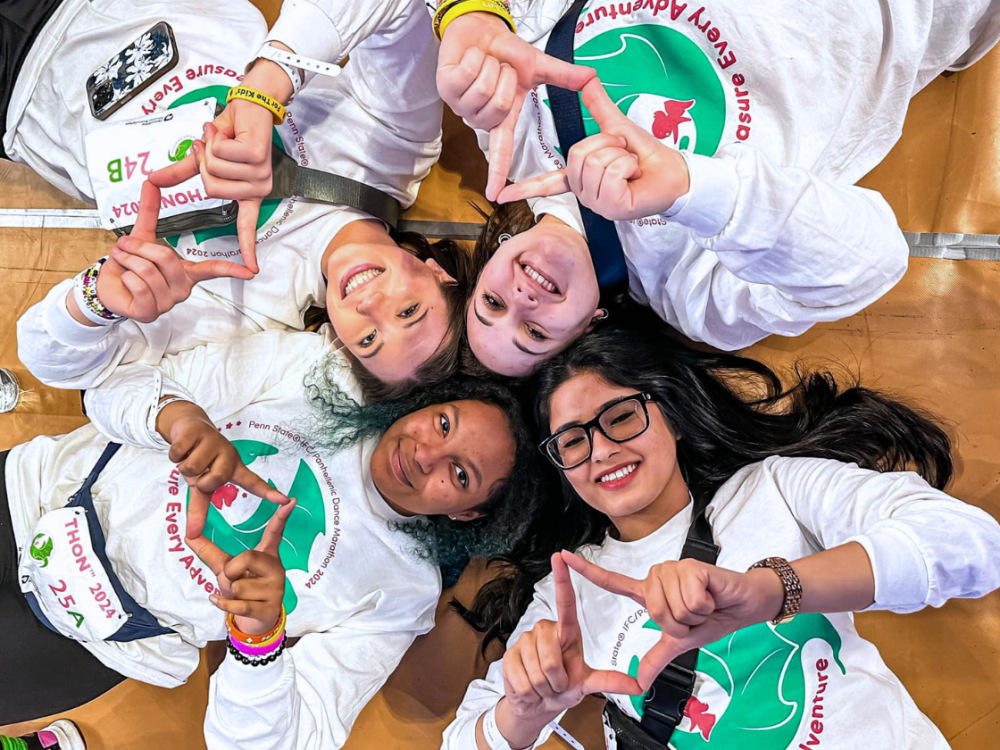 four young women lay on the ground in the shape of a diamond smiling 