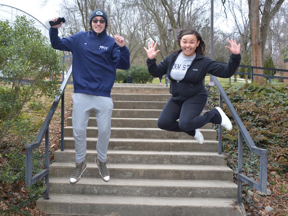 Male and female jump in the air on stepway on campus