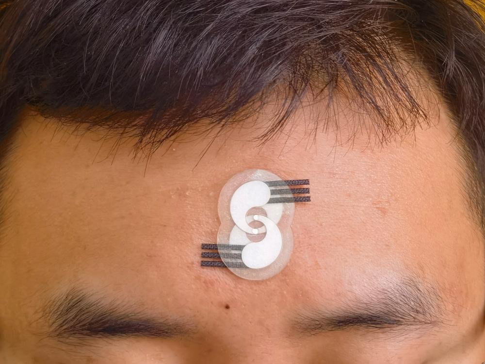 An electrochemical sensor is seen on a forehead.