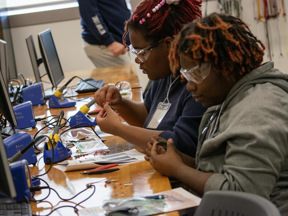 Two high school students work on a soldering activity