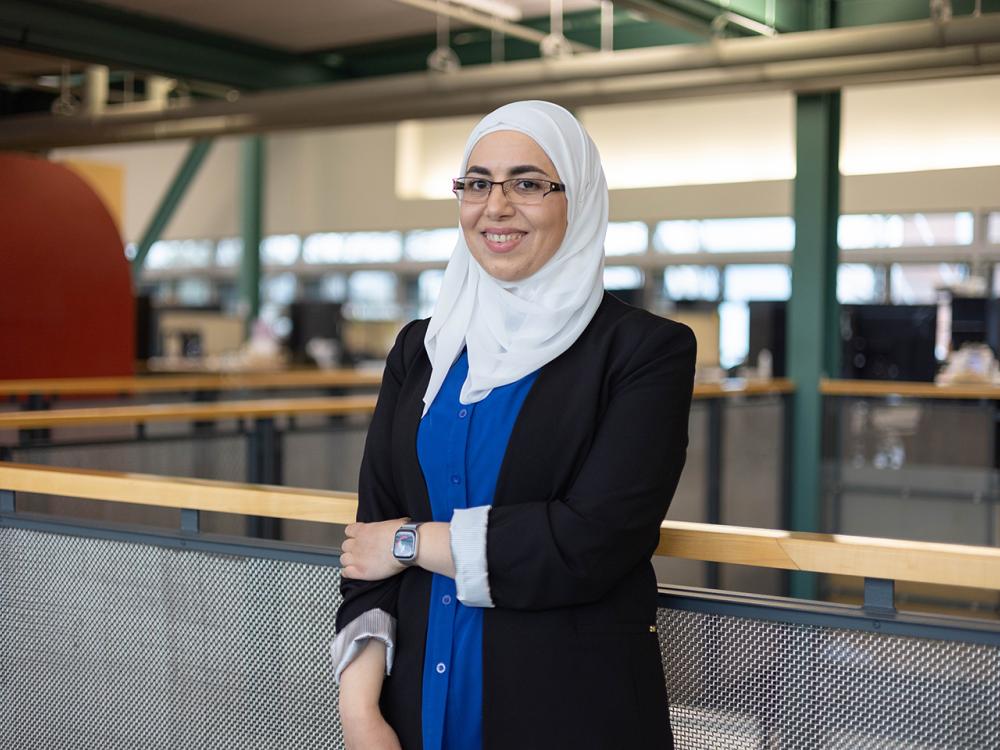 Dima Abu-Aridah in a white head scarf stands on the mezzanine level of the Stuckeman Family Building,