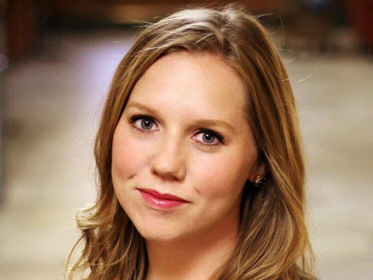 Headshot of Erika Crable, a white woman with long, dark blonde hair and blue yes wearing a dark top.