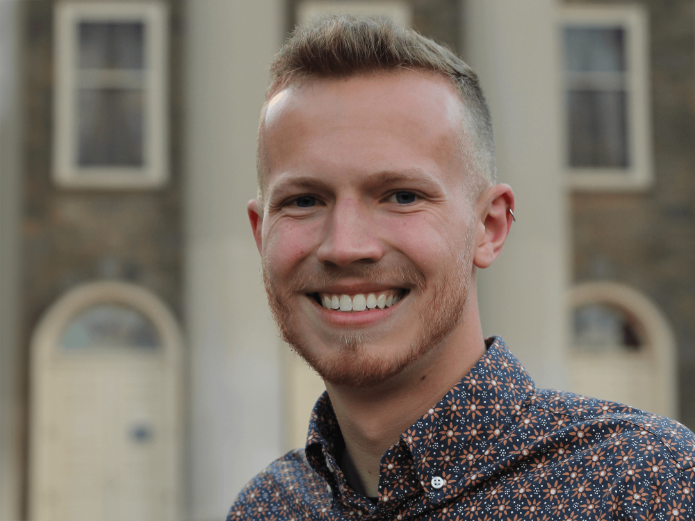 Harrison Brennan, a 2022 Penn State graduate, in front of Old Main 