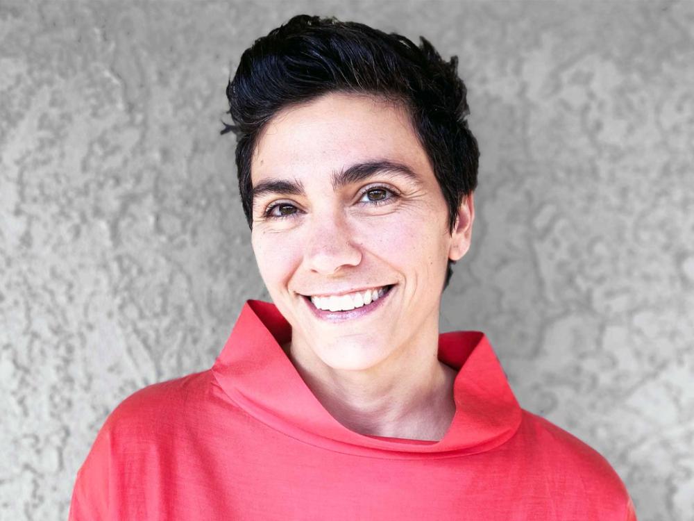 Alison Hirsch in a red shirt against a gray background 