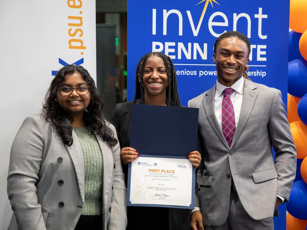 three smiling people display their first-place certificate