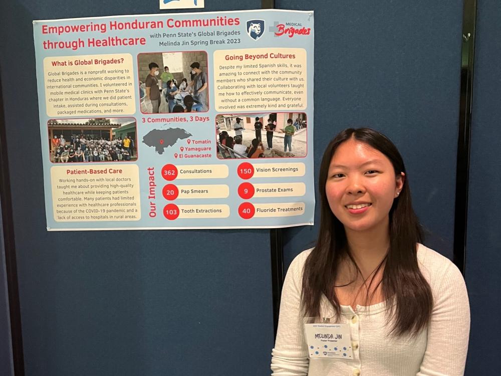 Melinda Jin posing for a photo in front of research poster