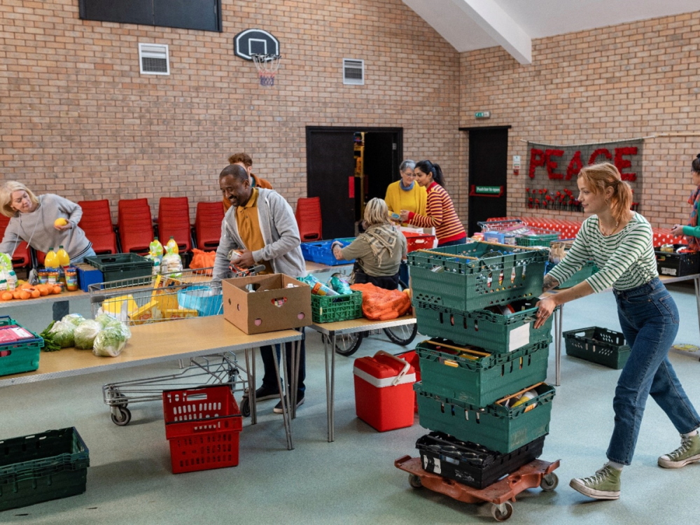 Several people work together in a food donation facility to organize food donations at a table. 