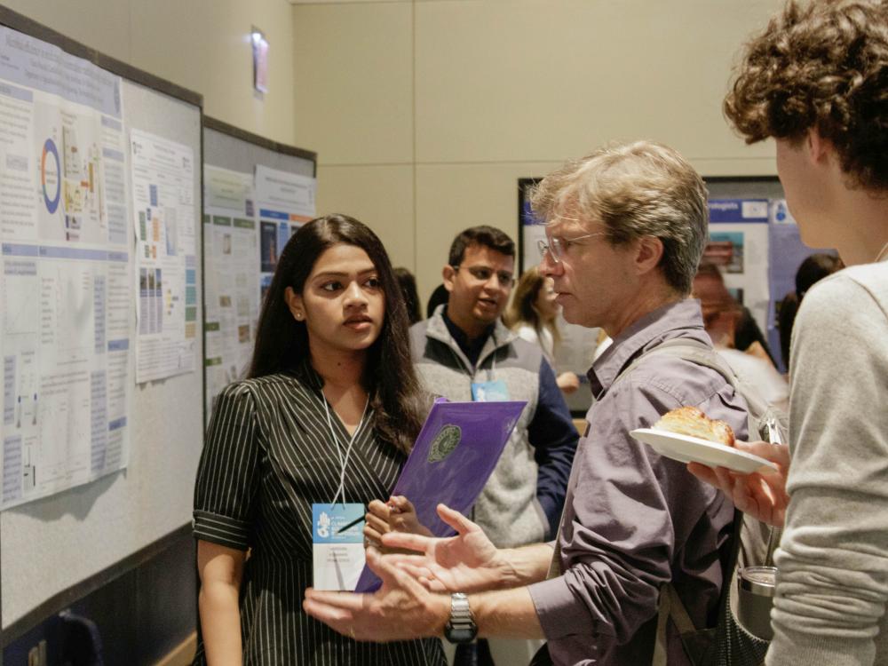 Ken Davis (second from right), professor of meteorology and atmospheric science, speaks with poster presenters at the 2023 Climate Solutions Symposium poster session.