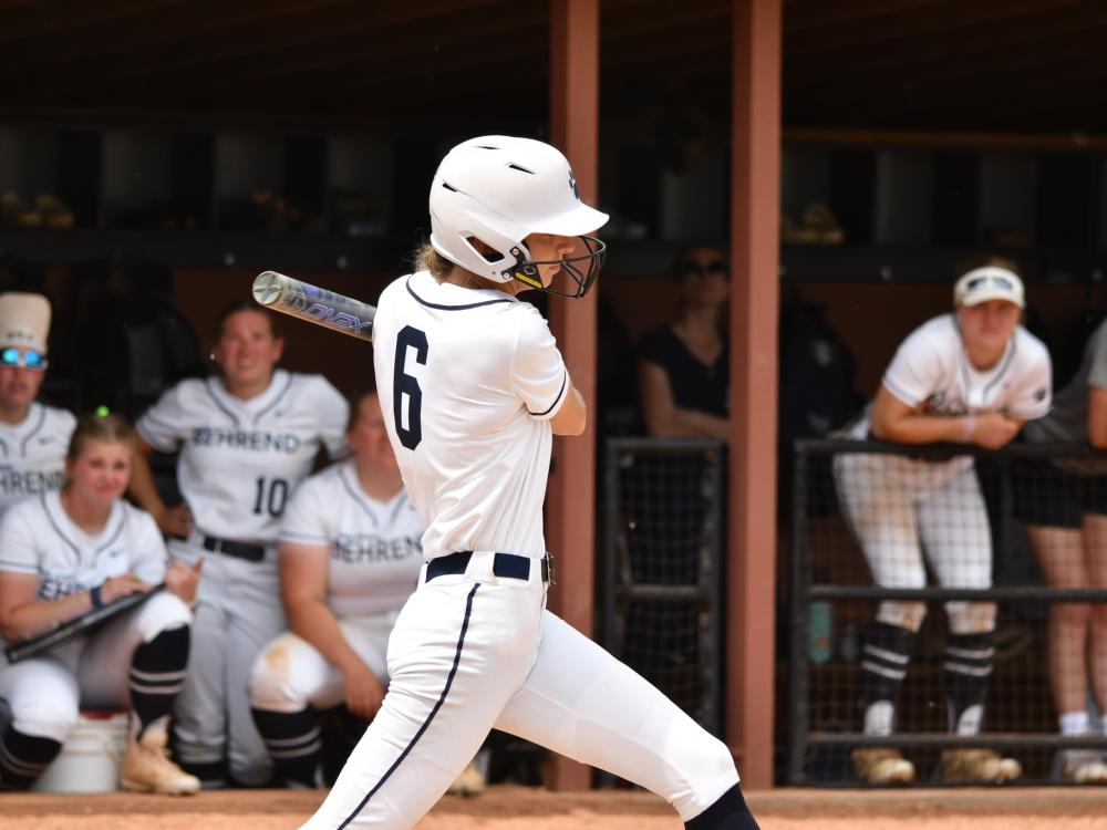 A Penn State Behrend softball player swings at a pitch.