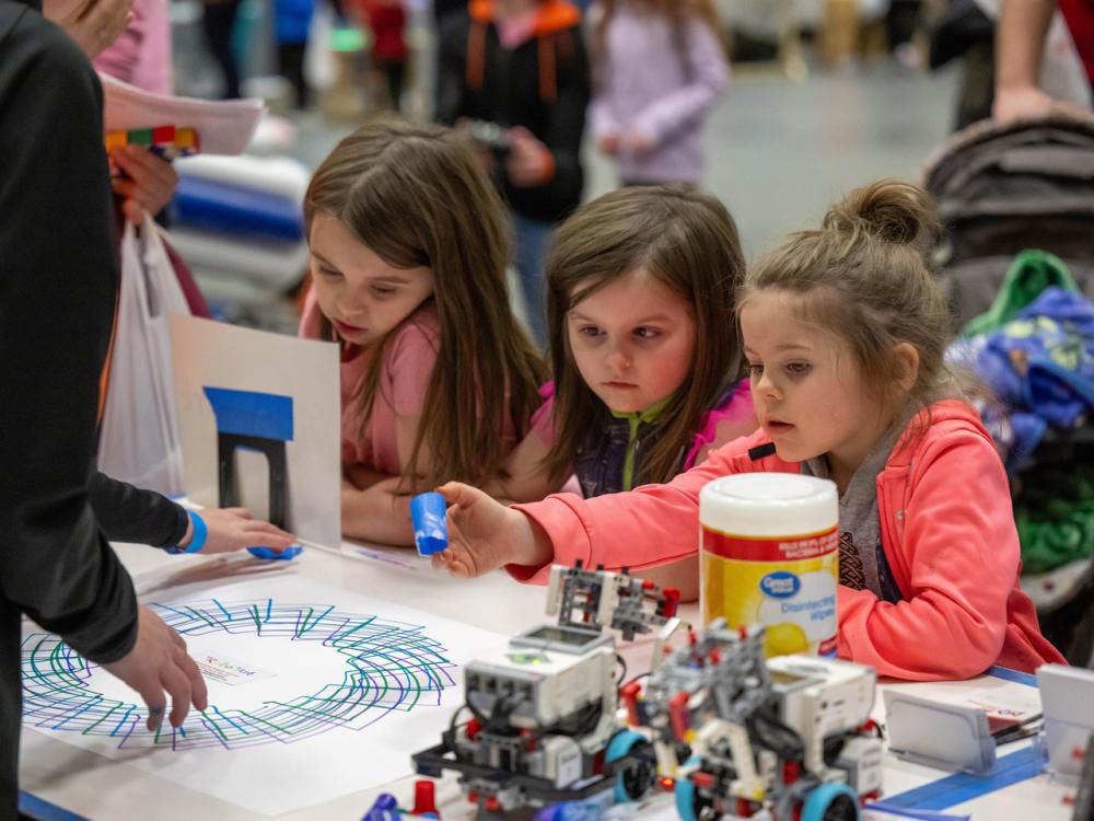 Three girls experiment with a robotic pen at Penn State Behrend's annual STEAM Fair.