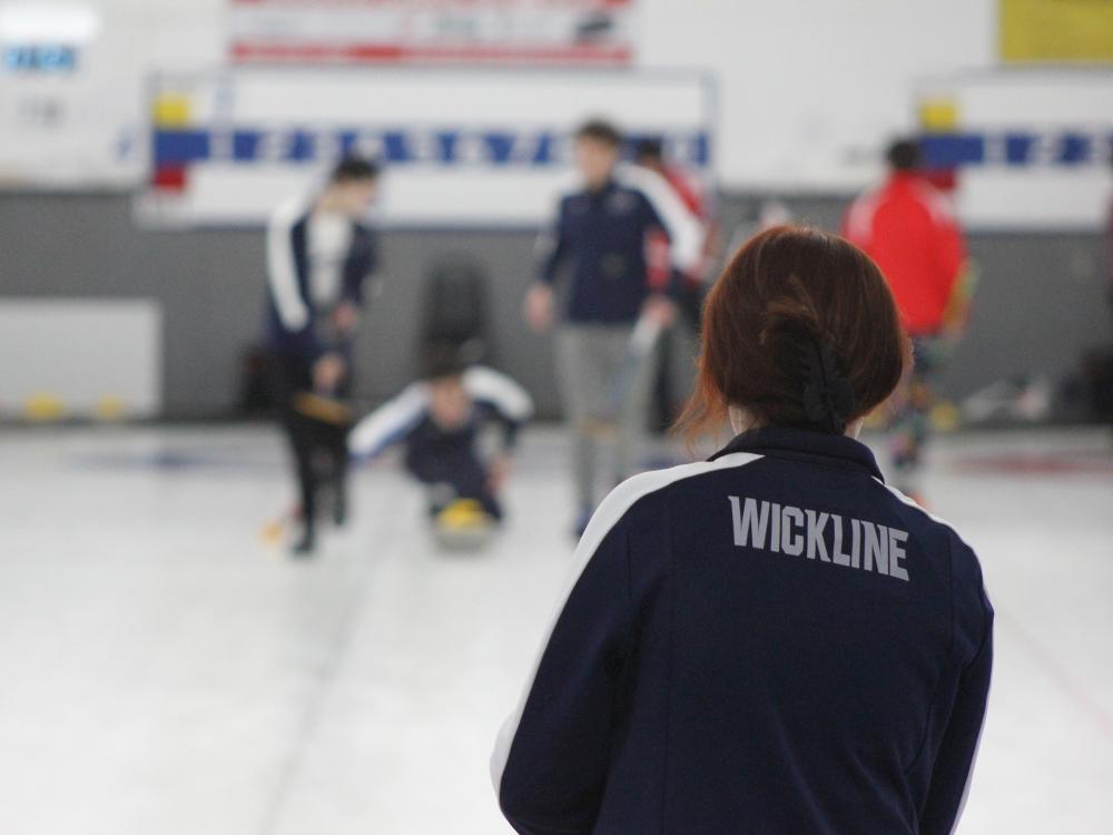 mallory wickline watching as her curling teammates take a shot