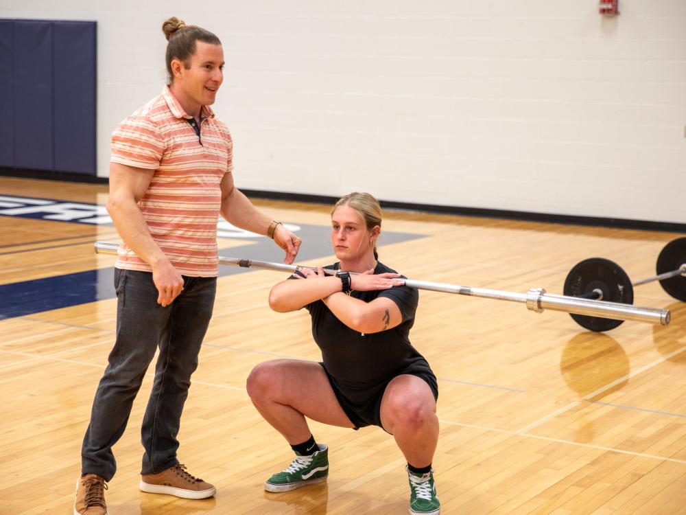 Student squats with lifting bar 