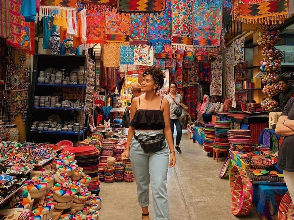 Woman walking among colorful tapestries in a street market