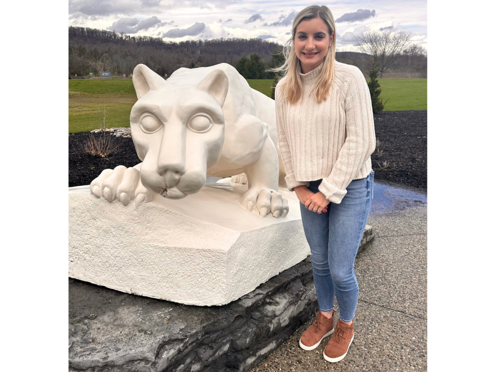 a female student standing in front of the lion shrine 