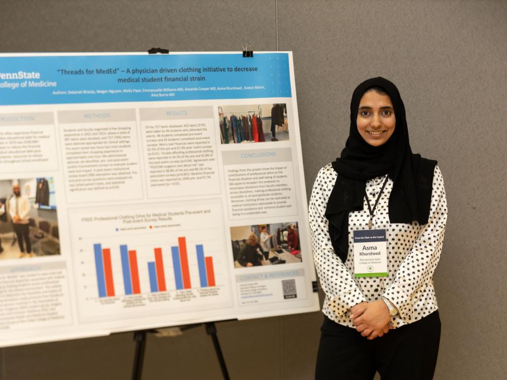 A woman standing in front of a poster presentation at a conference.