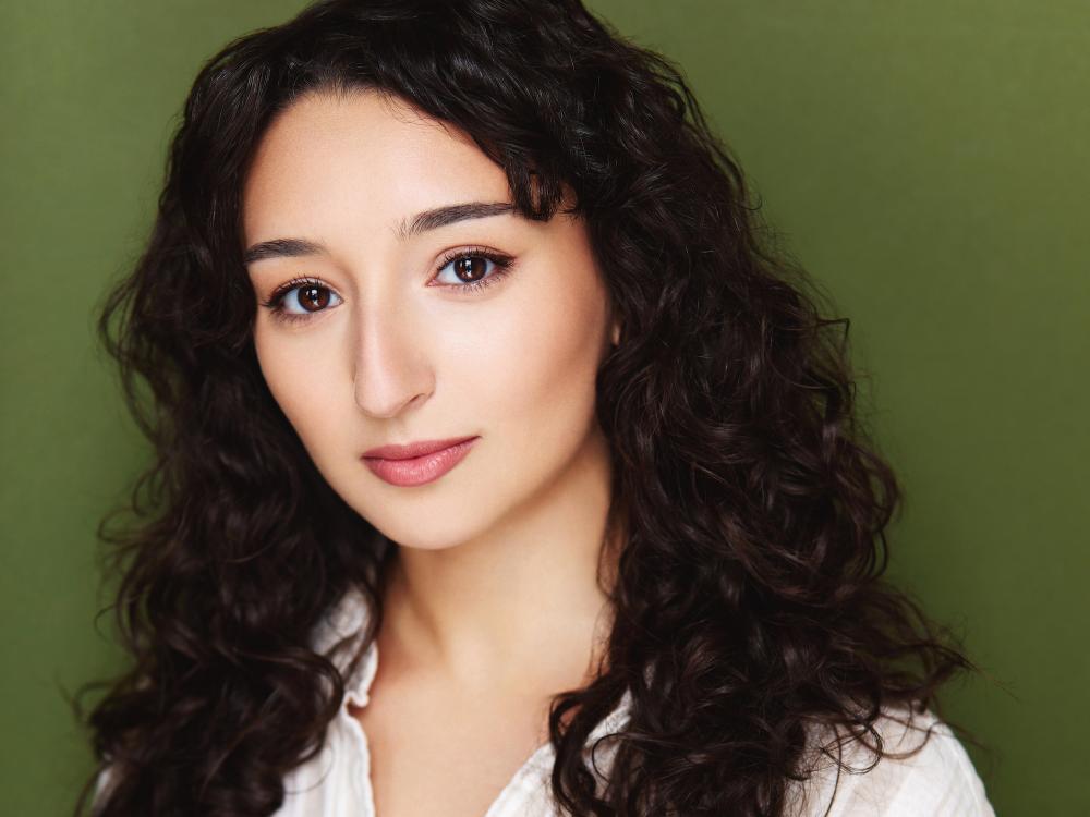 Head shot of a young woman with dark, wavy hair.