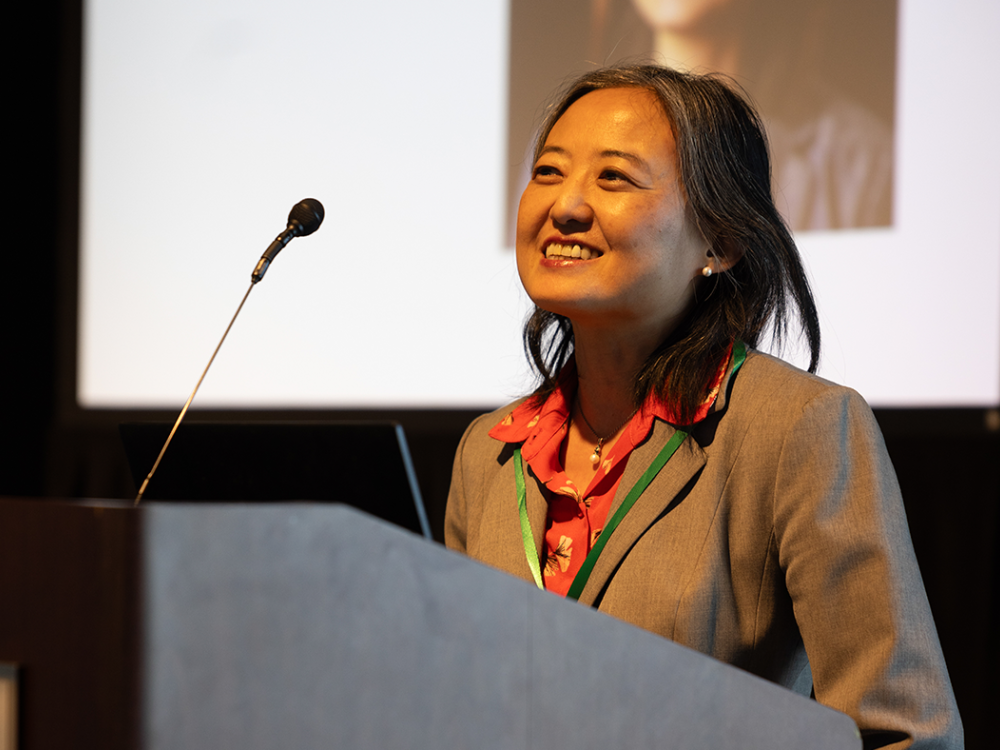 Chingwen Cheng standing at a podium smiling. 