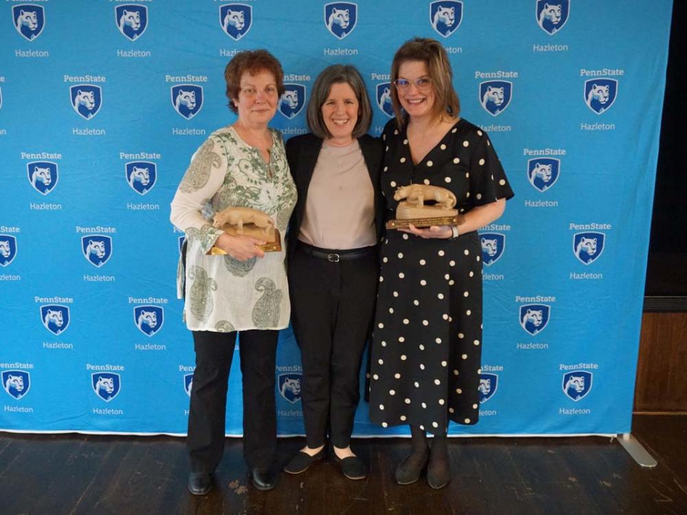 Three women standing in front of light blue Penn State Hazleton backdrop.