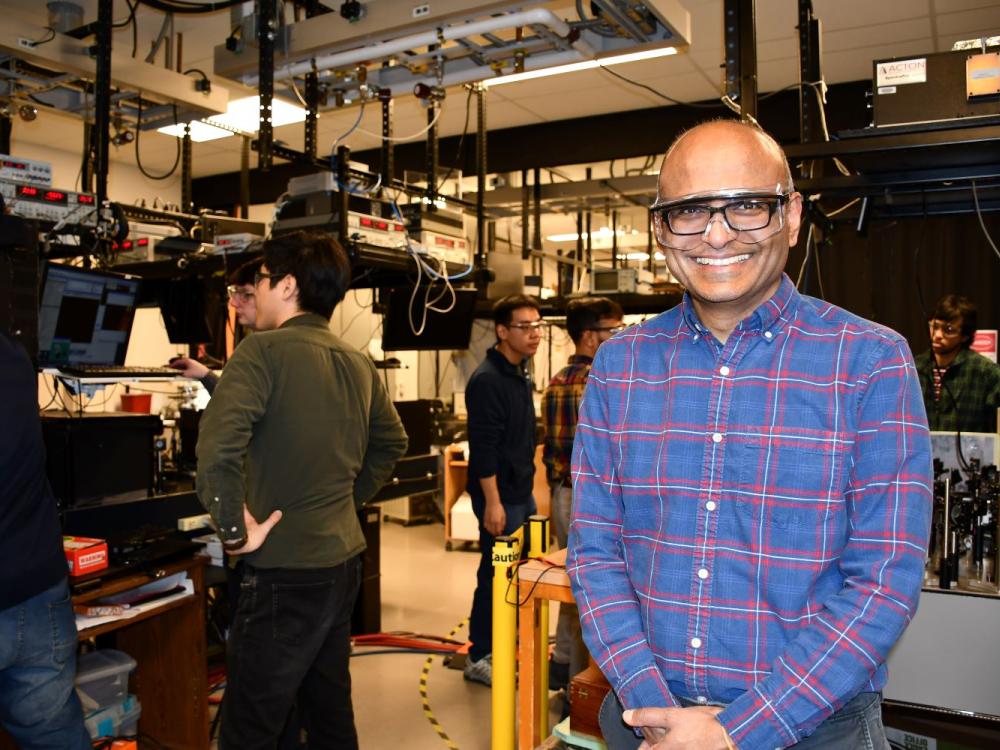 man standing in lab with people working behind him