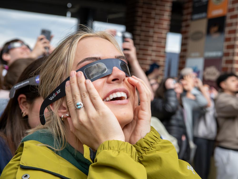 Woman wearing eclipse glasses looking up