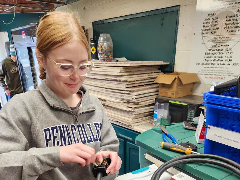 Haleymaria Hallock wires a new cord and plug onto a piece of kitchen equipment