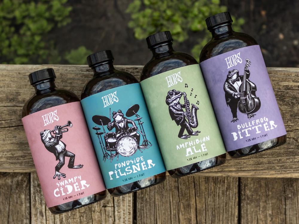 Four beer bottles for Hops brand beer featuring frogs playing musical instruments. 
