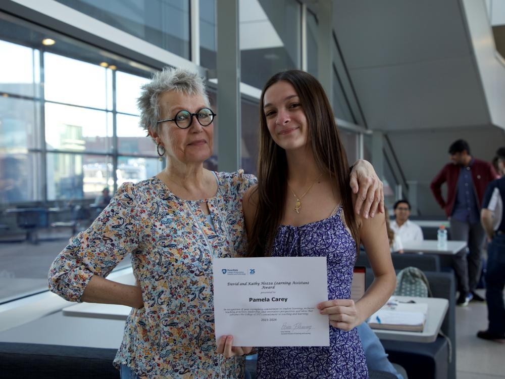 person with glasses presents certificate to person in dress