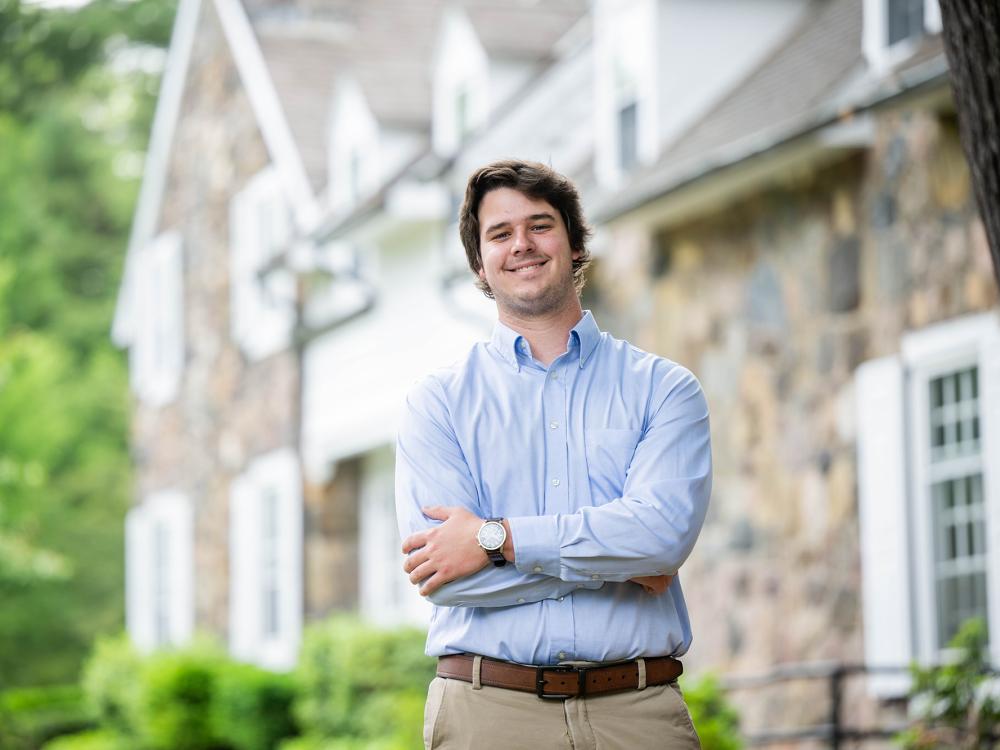 Josiah Burkett stands in front of Glenhill Farmhouse at Penn State Behrend.