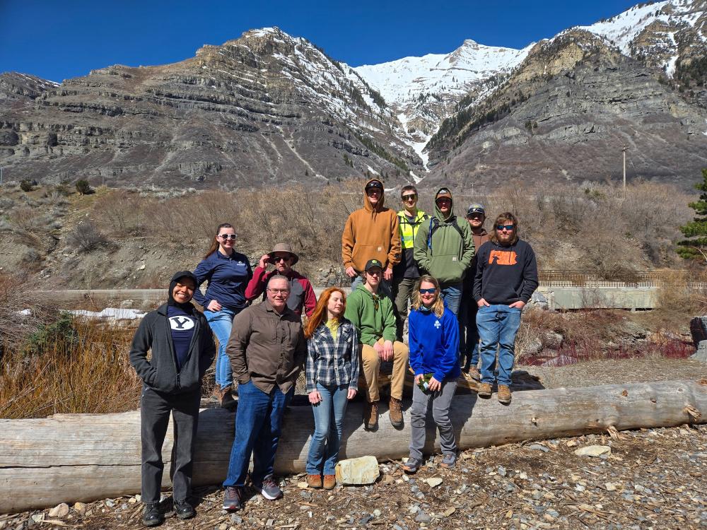 Penn College students, alumni and faculty stand for a group photo with mountains and blue skies behind them in Provo, Utah.